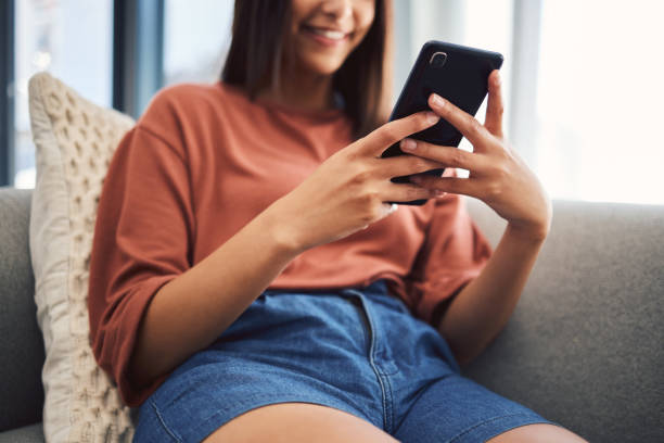 istock Close up of female hand's using smartphone to browse the internet, using mobile app or messaging on social network while sitting on the couch at home 1440167581