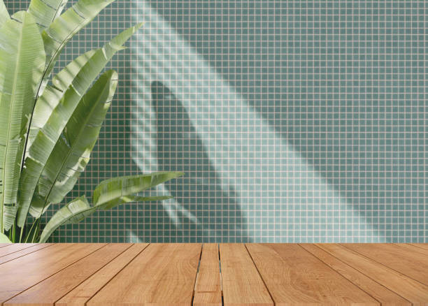 tampo de mesa ou bancada de madeira na parede de mosaico turquesa moderna com luz solar salpicada da janela e bananeira tropical em casa - turquoise blue spa treatment green - fotografias e filmes do acervo