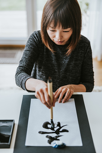 Japanese woman writing Kakizome- a traditional piece of calligraphy for the New Year.