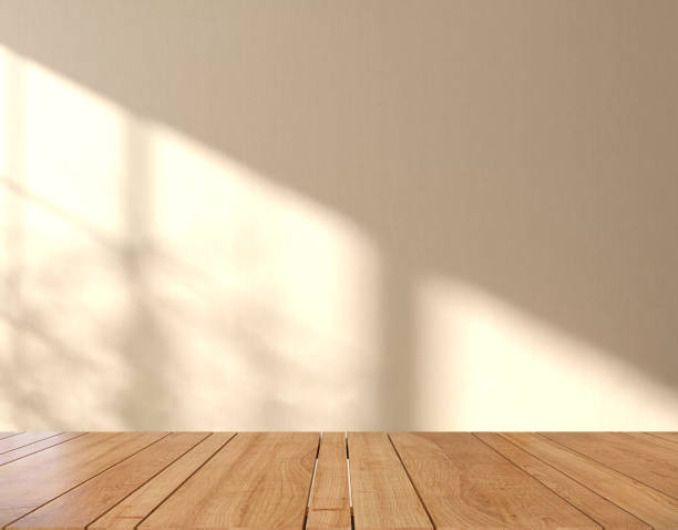 mesa o encimera de madera en una moderna y minimalista sala de pared marrón beige con luz solar moteada y sombra de árbol desde la ventana en casa - dappled light tree leaf fotografías e imágenes de stock