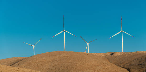 istock Multiple wind turbines standing on a hill at sunrise and generating electricity 1440170051