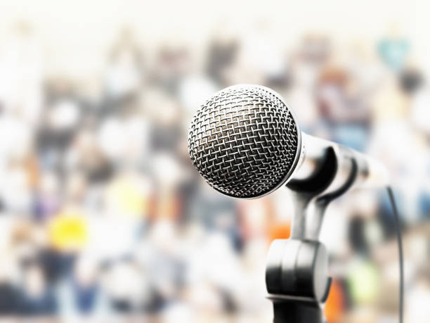 istock Vocal microphone in front of a blurred crowd of people 1440173386