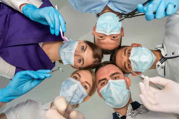 A large group of motivated doctors and nurses standing in a circle and joking with each other. A large group of motivated doctors and nurses standing in a circle and joking with each other. The concept of happiness being a doctor dental drill stock pictures, royalty-free photos & images