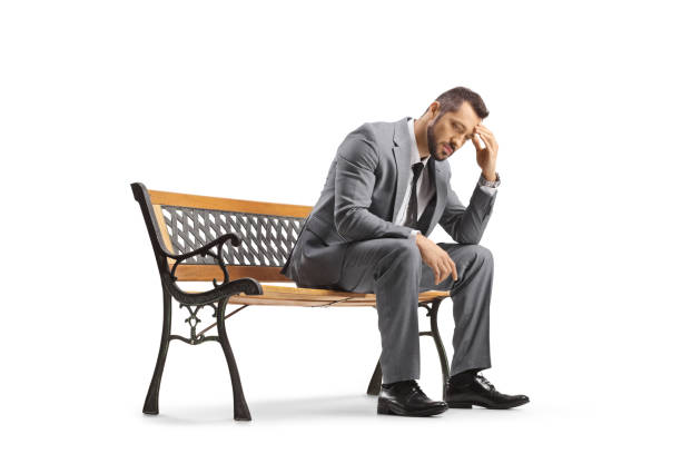 Sad businessman sitting on a bench and holding his head isolated on white background