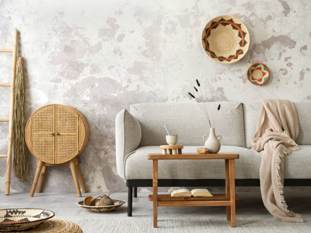istock Creative composition of ethnic living room interior with grey sofa, colorful wicker, rattan sideboard, vase with dried flowers, wooden coffee table and personal accessories. Home decor. Template. 1440179018