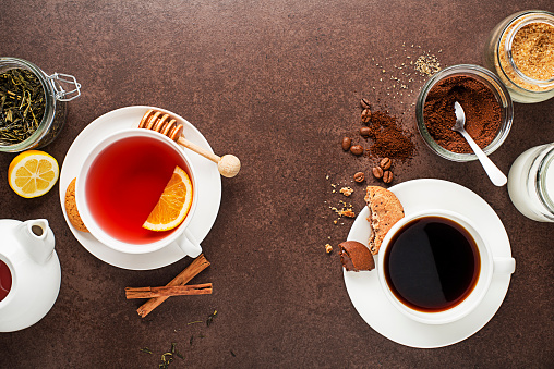 Cups of hot coffee and tea with ingredients on dark background