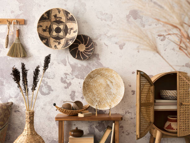 istock Creative composition of ethnic living room interior with design, colorful baskets, rattan sideboard,  wooden consola, round plate, gray concrete wall, and personal accessories. Home decor. Template. 1440179103