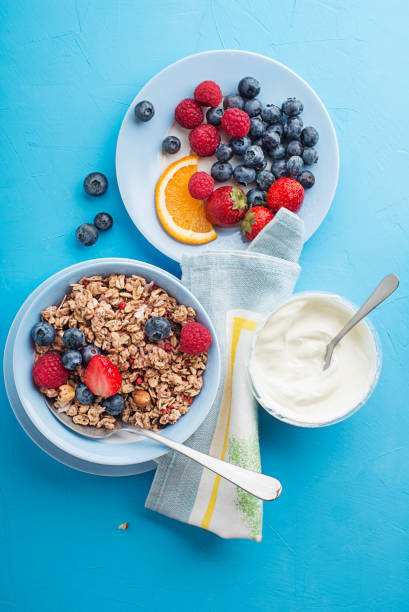 A bowl of dry granola served with fresh berry fruit and yogurt. Oatmeal plate. Healthy food, diet. Top view.
