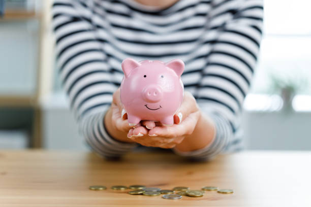Woman hands holding piggy bank on wooden table. Saving money and financial investment stock photo