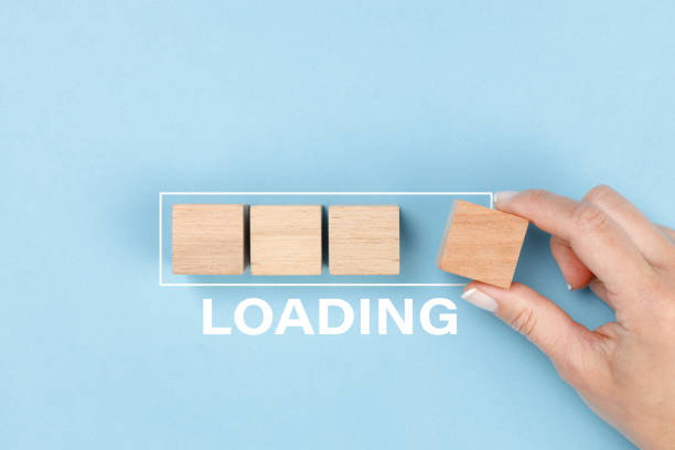istock Hand putting wooden blocks in progress bar on blue background with the word Loading. Loading, reboot, refresh or mindset concept. 1440180789