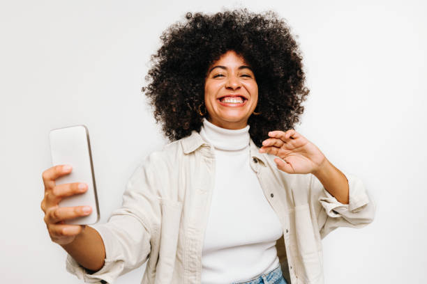 istock Gorgeous woman with curly hair taking a selfie in a studio 1440181482