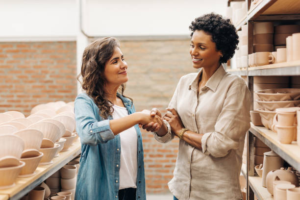 istock Two female ceramists shaking hands in a ceramic shop 1440181617