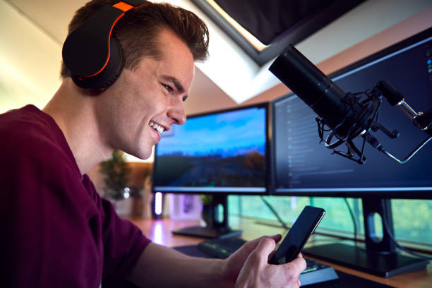 istock Man With Mobile Phone Gaming At Home Sitting At Desk With Multiple Monitors 1440183089