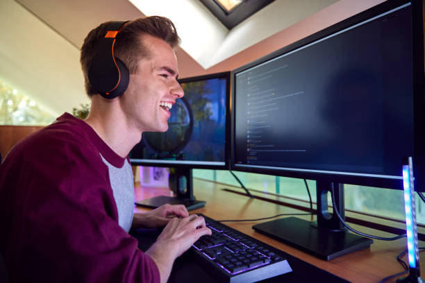 istock Man Gaming At Home Sitting At Desk With Multiple Monitors 1440183160