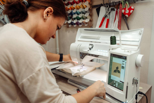 istock A woman tailor makes embroidery on an embroidery machine in a home workshop.Mending clothes concept,small business. 1440184055