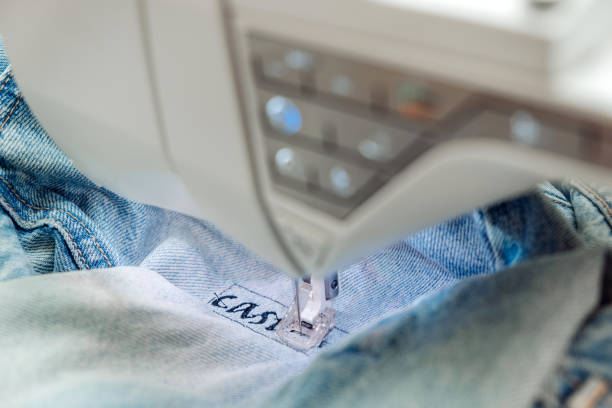 an embroidery machine embroider a pattern on jeans.mending clothes concept,reusing old jeans. - embroider imagens e fotografias de stock