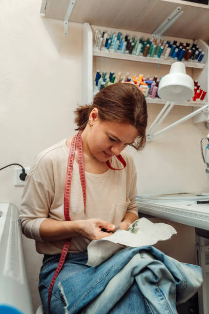 istock A woman mends jeans, sews a patch on a hole in the home studio.Mending clothes concept,reusing old jeans.Small business 1440184334