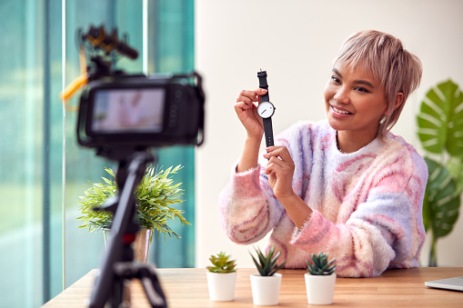 Female Vlogger Recording Wristwatch Product Review Video At Home With Camera