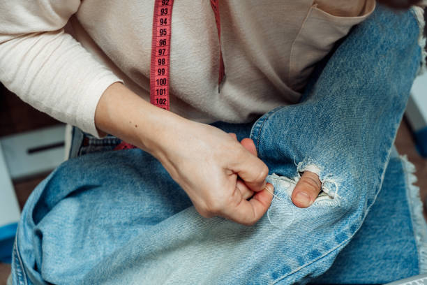 istock A woman mends jeans, sews a patch on a hole, hands close-up.Mending clothes concept,reusing old jeans 1440184438