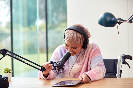 Woman Recording Podcast Or Broadcasting On Radio In Studio At Home With Digital Tablet