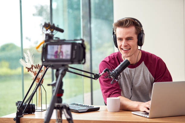 istock Male Vlogger With Laptop Recording Video At Home With Camera 1440184554