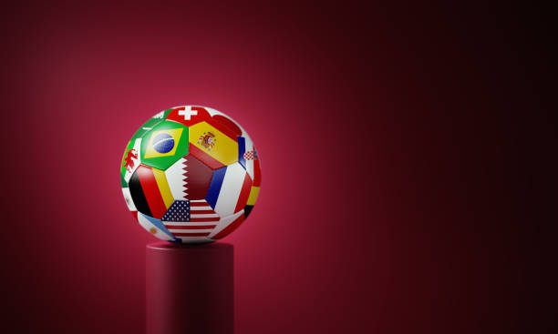 Soccer ball textured with national flags sitting on cherry colored podium before cherry colored background.  Horizontal composition with copy space.