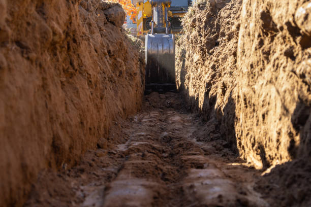 Excavator Digging a Trench for House Foundation Excavator digging a trench ditch for a small house foundation earthwork stock pictures, royalty-free photos & images