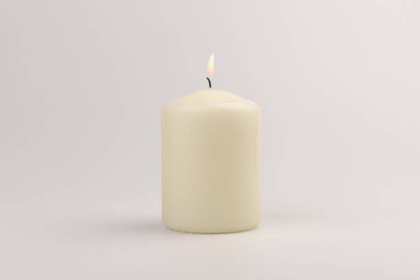 Burning white wax candles on white background.