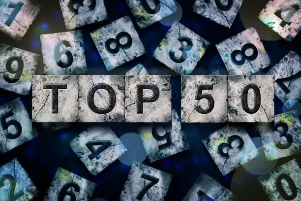 Photo of Top 50, words, above different numbers, on a dark blue background, with different letters. Alphabet on stone blocks.Rating. Rating concept.