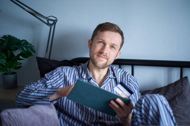 istock Male lying on bed using tablet for shopping on black friday with credit card 1440187803