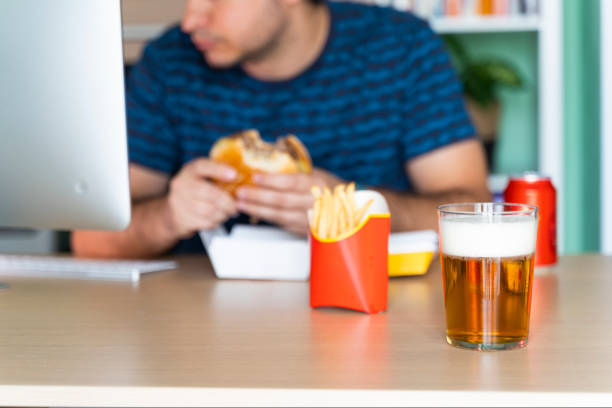 istock Man eating fast food while working in his office in front of the computer 1440189828