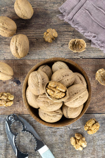 istock Walnut kernels and whole walnuts on a wooden table. View top view. Top view, flat lay with space for placement. Nuts and nutcracker on a wooden background. 1440192032