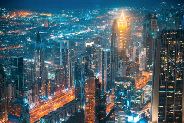 Aerial view of city background of illuminated cityscape with skyscrapers and modern urban architecture in Dubai resort town. Street night traffic In Dudai skyline. United Arab Emirates. High quality photo. vista aérea del fondo de la ciudad de paisaje urbano iluminado con rascacielos y arquitectura urbana moderna en la ciudad turística de dubai. tráfico nocturno en la calle en el horizonte de dudai. emiratos Árabes unidos. foto de alta calidad