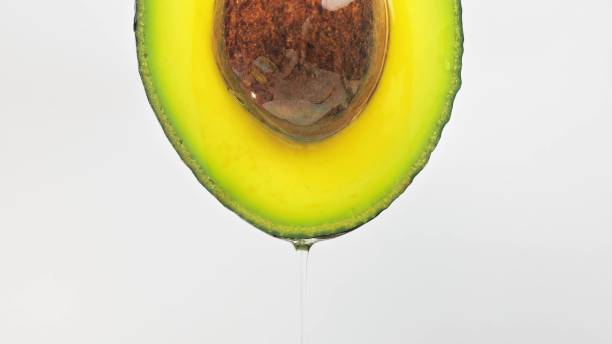 slow motion close-up of fresh avocado fruit and oil flowing on white background - avocado oil bildbanksfoton och bilder
