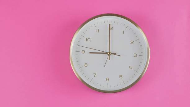 the clock shows 9 o'clock on a pink background