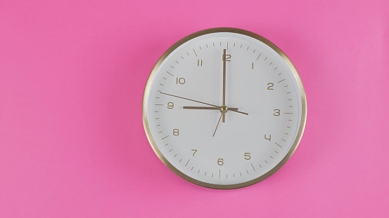 the clock shows 9 o'clock on a pink background.