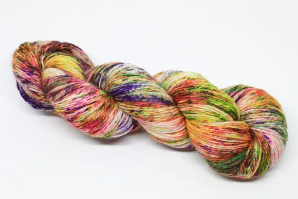Beautiful skein of colourful handdyed sockyarn for knitting, laying on a white background.