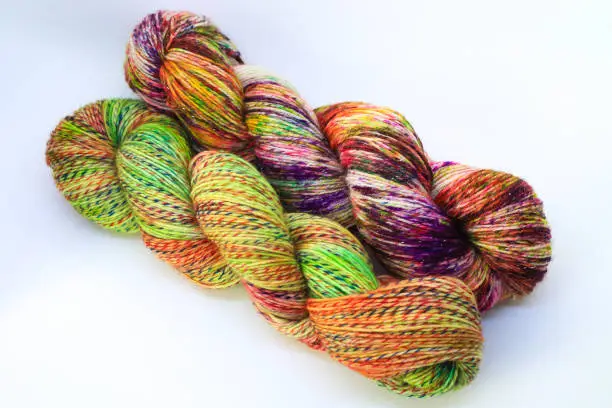 Beautiful skein of colourful handdyed sockyarn for knitting, laying on a wooden floor as a background.