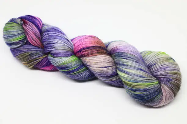 Beautiful skein of colourful handdyed sockyarn for knitting, laying on a white background.