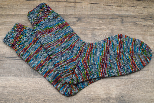 Bright handmade socks on a white wooden background.Knitted warm, winter socks. Wool yarn. winter hobbies. Hobby.Place for text, space for copy.
