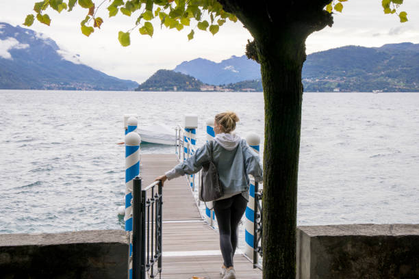 istock Young woman walks down dock on lake 1440200118