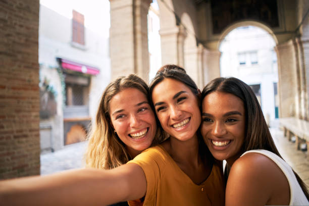 istock three happy female friends having fun together and taking smiling selfie 1440200192