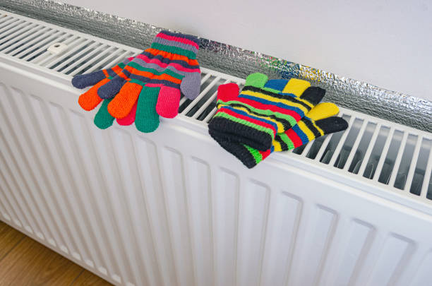 Warm multicolored child's gloves on the radiator heating. Heating season at home, concept. Knitted Gloves stock pictures, royalty-free photos & images