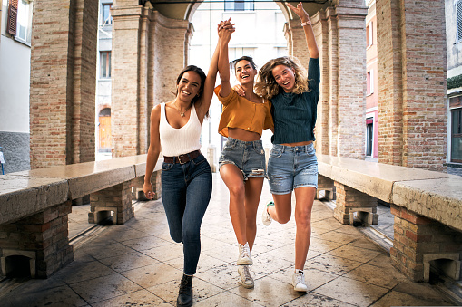 Young happy women happy running to camera laughing excited. Cheerful people making holidays in European city. High quality photo