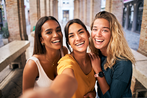 Three young smiling 20s young girls in summer clothes. Women taking selfie self portrait photos on smartphone. High quality photo
