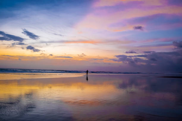 silueta de un hombre sobre el fondo de mar en calma con cielo al atardecer y sol a través de las nubes encima. meditación océano y cielo de fondo. paisaje marino tranquilo. horizonte sobre el agua - sky landscape horizon over water sunlight fotografías e imágenes de stock