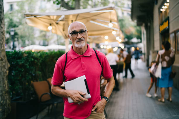 istock Caucasian elderly person in optical spectacles for provide eyes correction looking at camera during travel weekend, senior blogger holding digital gadget and posing at urban street of city 1440207719