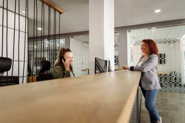 istock Receptionist assisting a woman standing at front desk office reception 1440208588