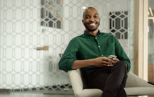 istock African man sitting at bank reception holding smartphone looking into camera 1440208598