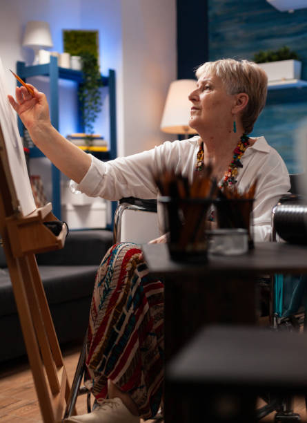istock Old woman drawing on canvas using pencil 1440213353